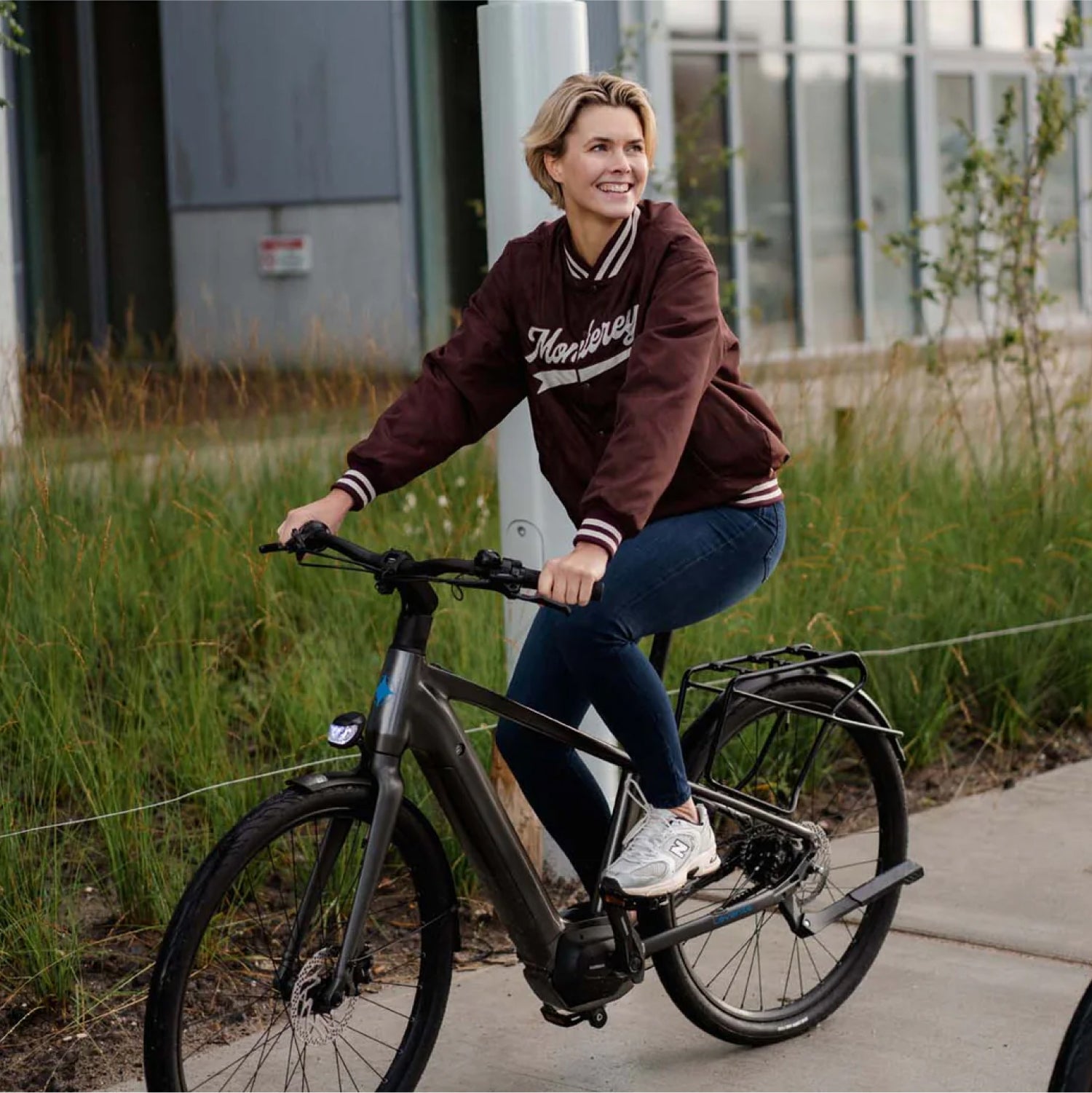 Blonde lachende vrouw op donkergrijze Levante E4 e-bike voor grasveld